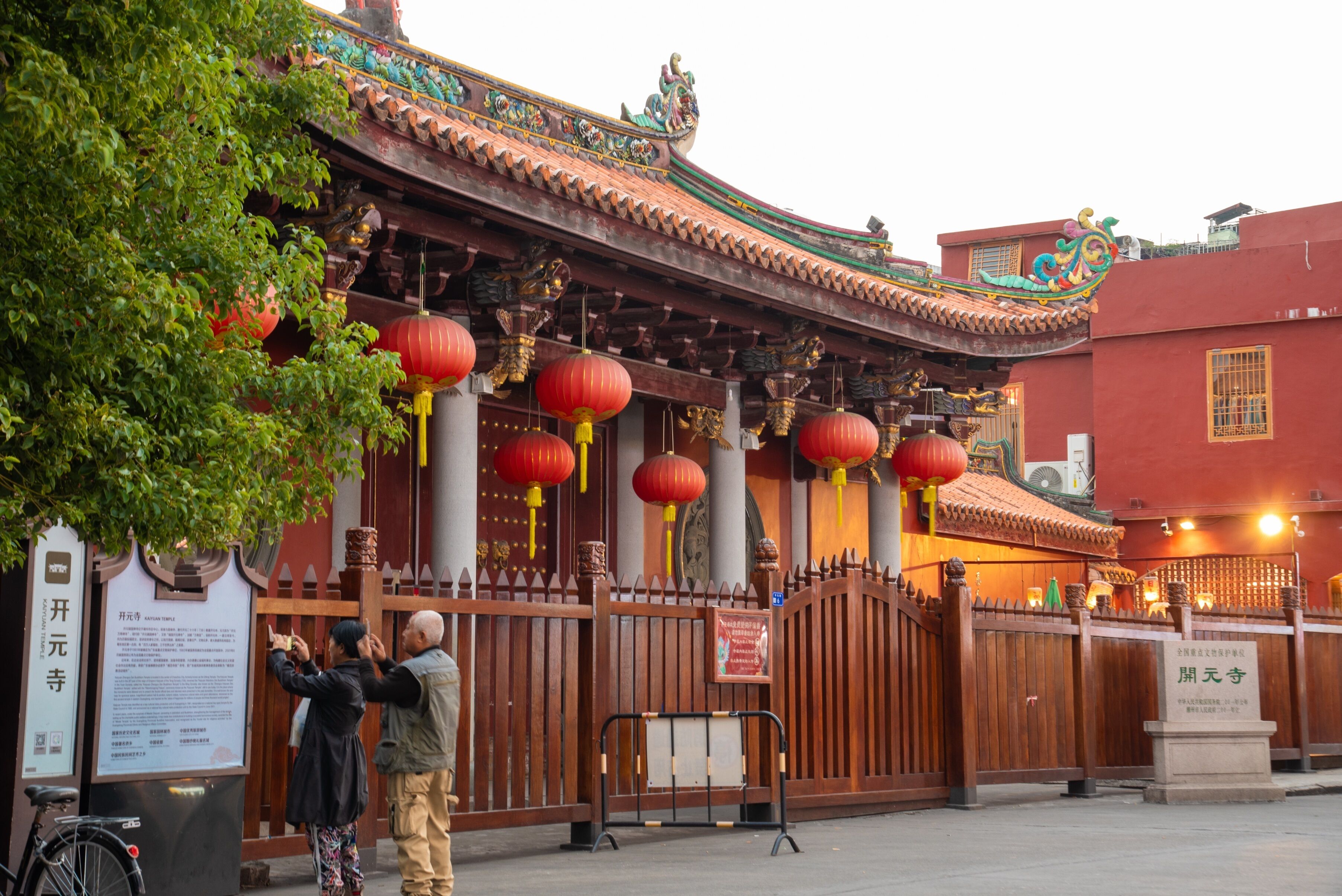 A traditional building with a red roof, ornate decorations, and red lanterns.