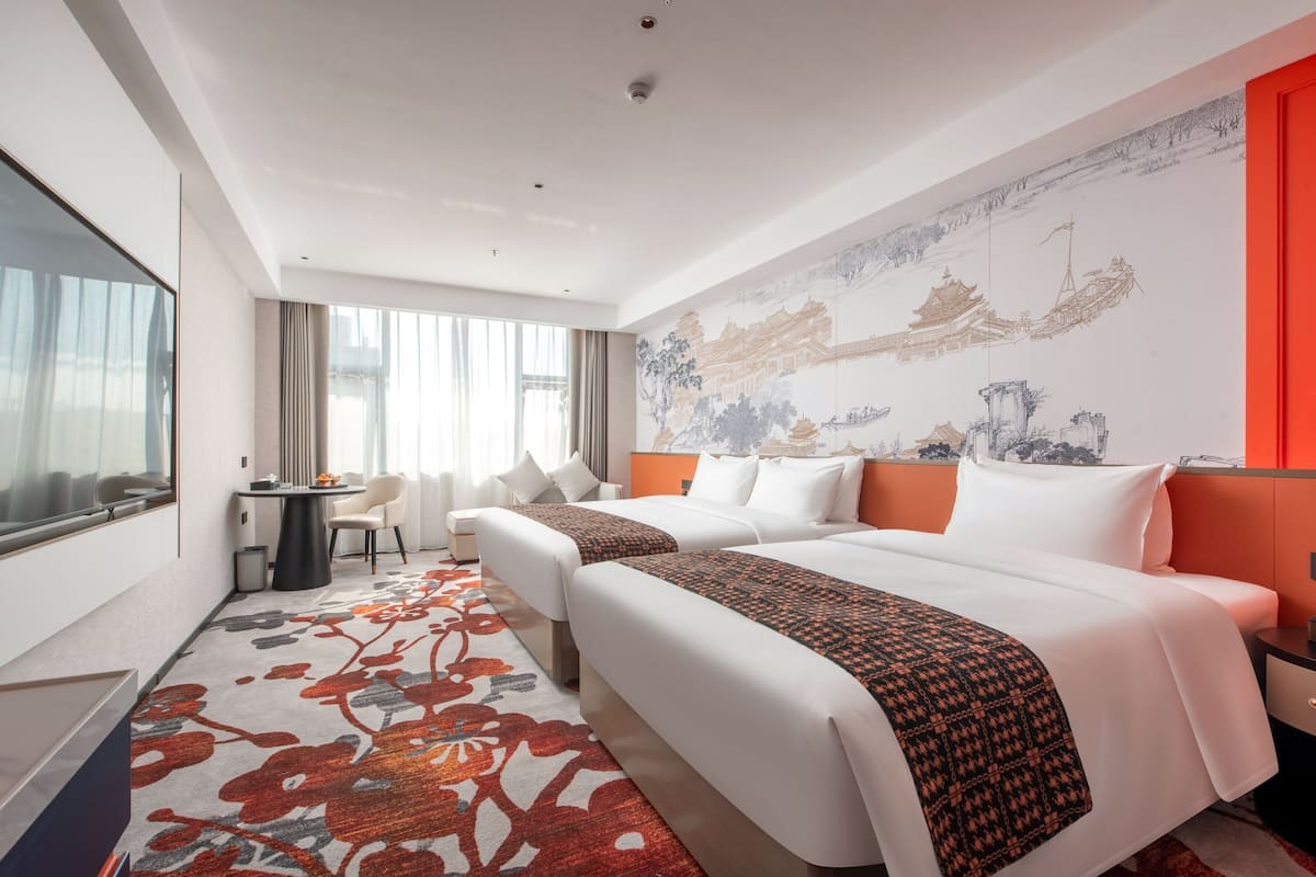 Ein Hotelzimmer mit zwei Betten, einem Schreibtisch und einem Sessel.
