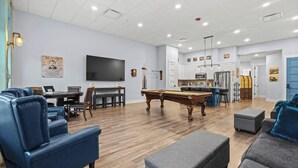 Un salon spacieux équipé d’une table de billard, de sièges confortables, d’un téléviseur à écran plat et d’un coin cuisine.