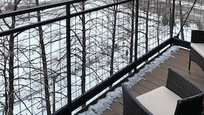 Un balcon offrant une vue sur un paysage enneigé et sur des bâtiments en arrière-plan.
