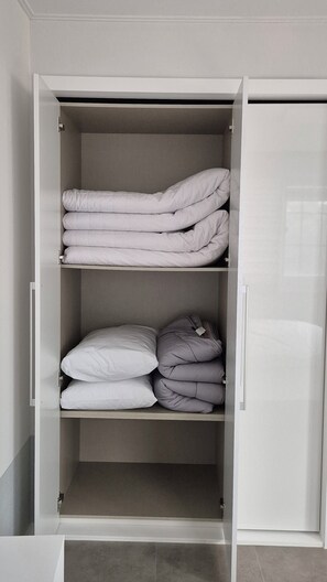 Ein Schrank mit zwei Einlegeböden, auf denen gefaltete Bettwäsche liegt.