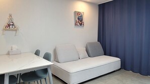 A modern room with a white sofa, a dining table with chairs, and a ceiling light. - pacific (Gyeongju)