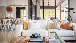 A modern living room with a white sofa, a wooden coffee table, and a telescope on the right.