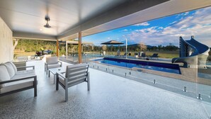 A modern outdoor lounge area with a pool, seating, and a view of the landscape.