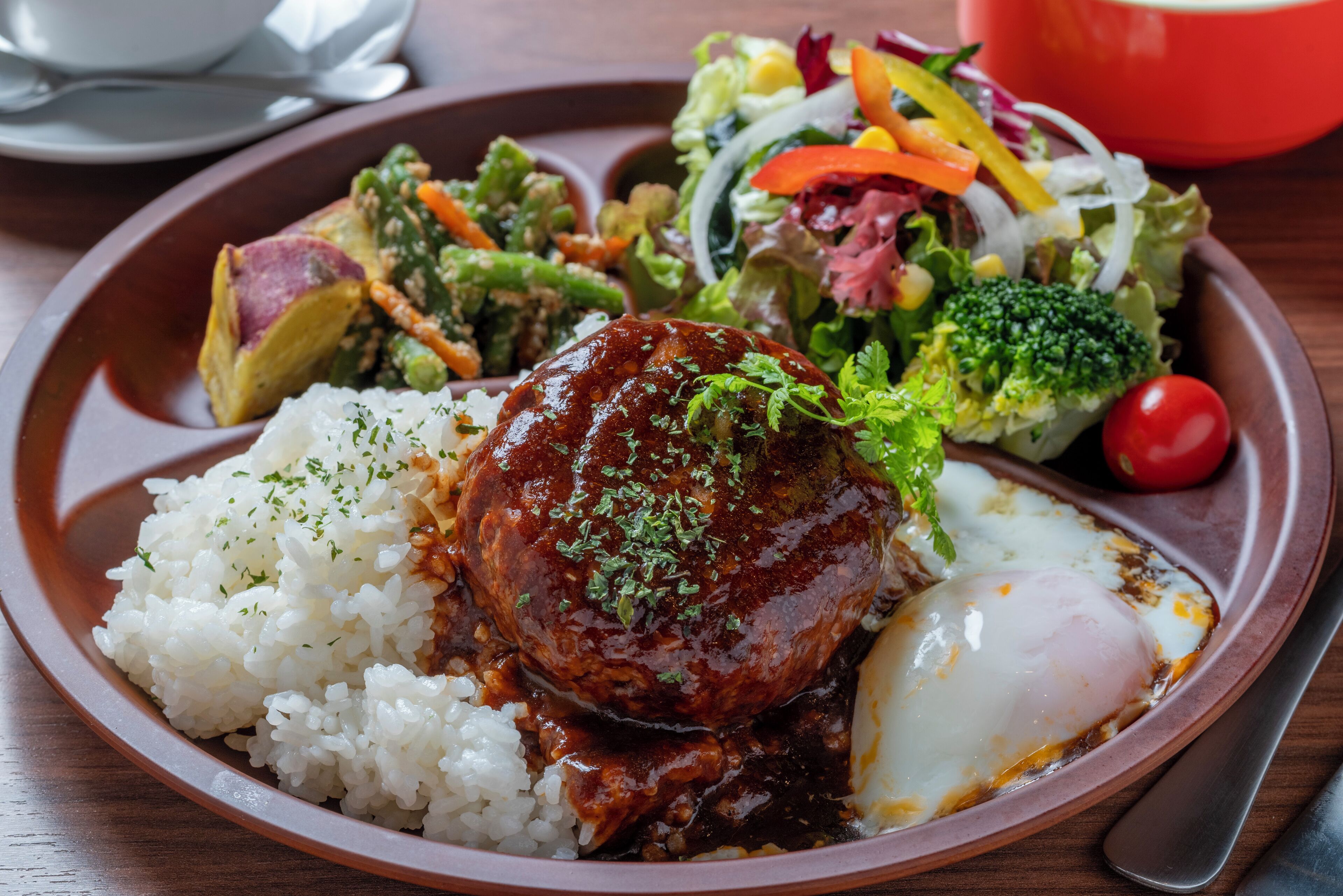 A plate with rice, a meat patty, a poached egg, and a side salad.