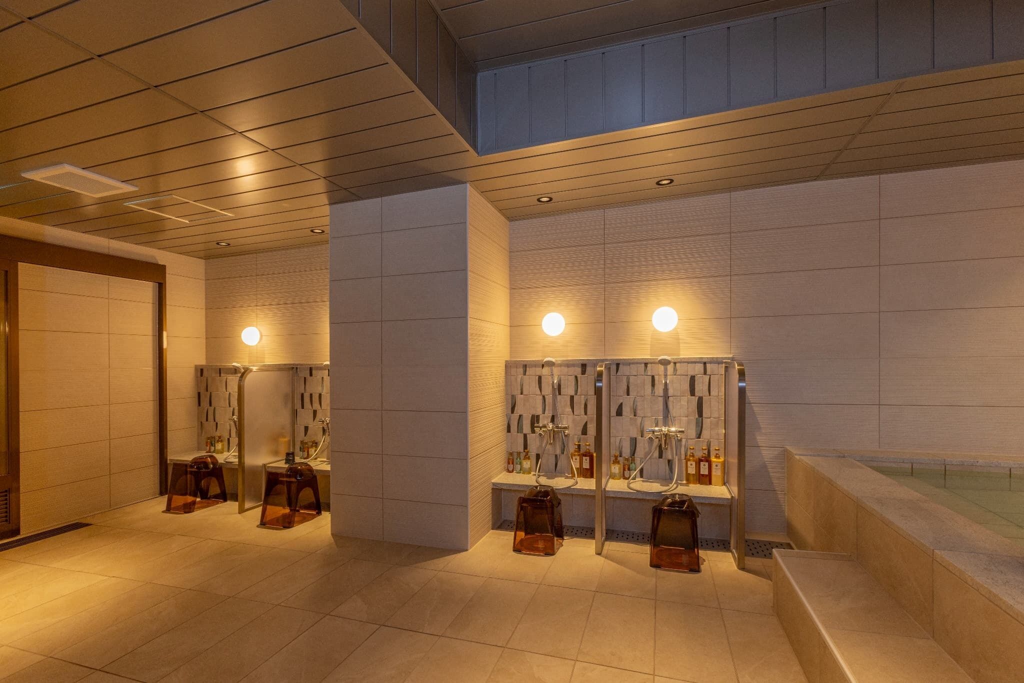 Une salle de bain moderne dotée de plusieurs lavabos, de bancs et d’une baignoire.