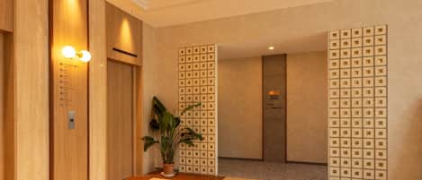 A hotel lobby with wooden paneling, a potted plant, and a tiled floor.