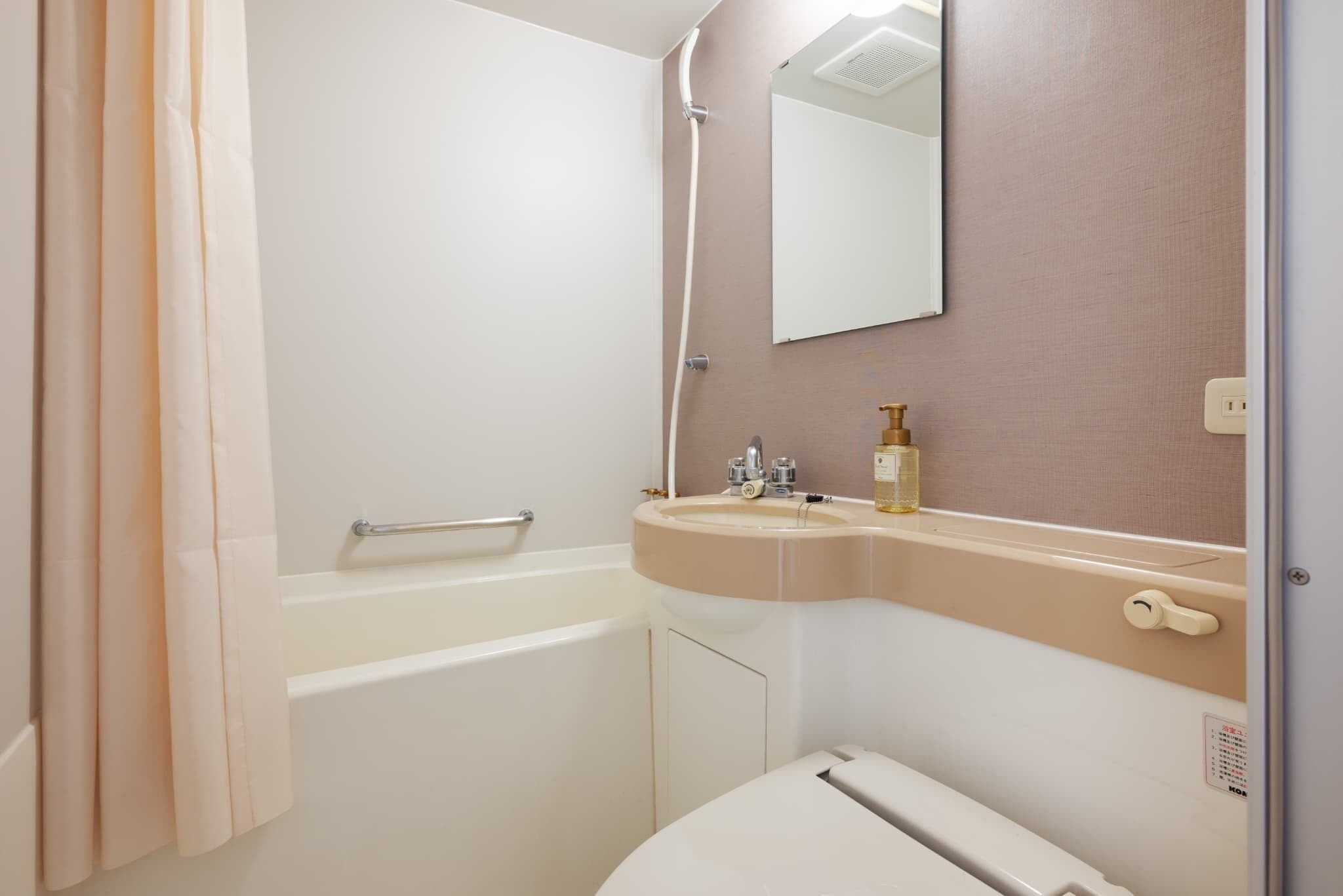 A bathroom with a bathtub, a sink, a mirror, and a toilet.