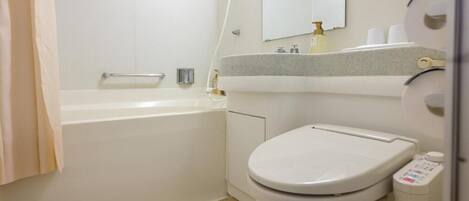 A bathroom with a white bathtub, a toilet, and a sink with a mirror above it.