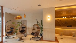 A reception area with wicker chairs, a reception desk, and a potted plant. - Hotel Global View Iwaki (Iwaki)