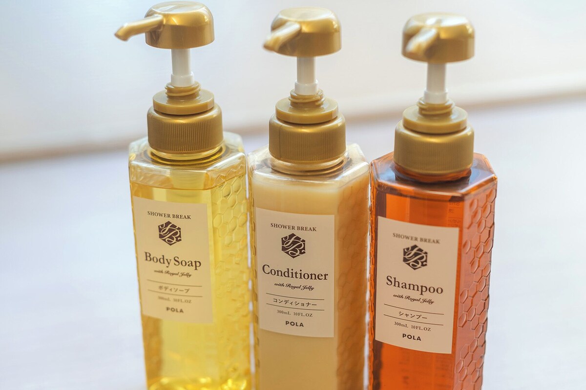 Three bottles of shower products with pumps, labeled as body soap, conditioner, and shampoo, each with a similar design and branding.