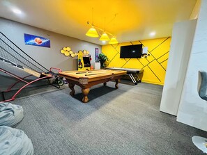 Ein Billardraum mit Billardtisch, Snookertisch und einem Fernseher an der Wand.