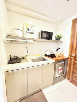 A compact kitchen with a microwave, kettle, and a sink. - MR BED-Skyline View Condo With POOL (Cebu City)