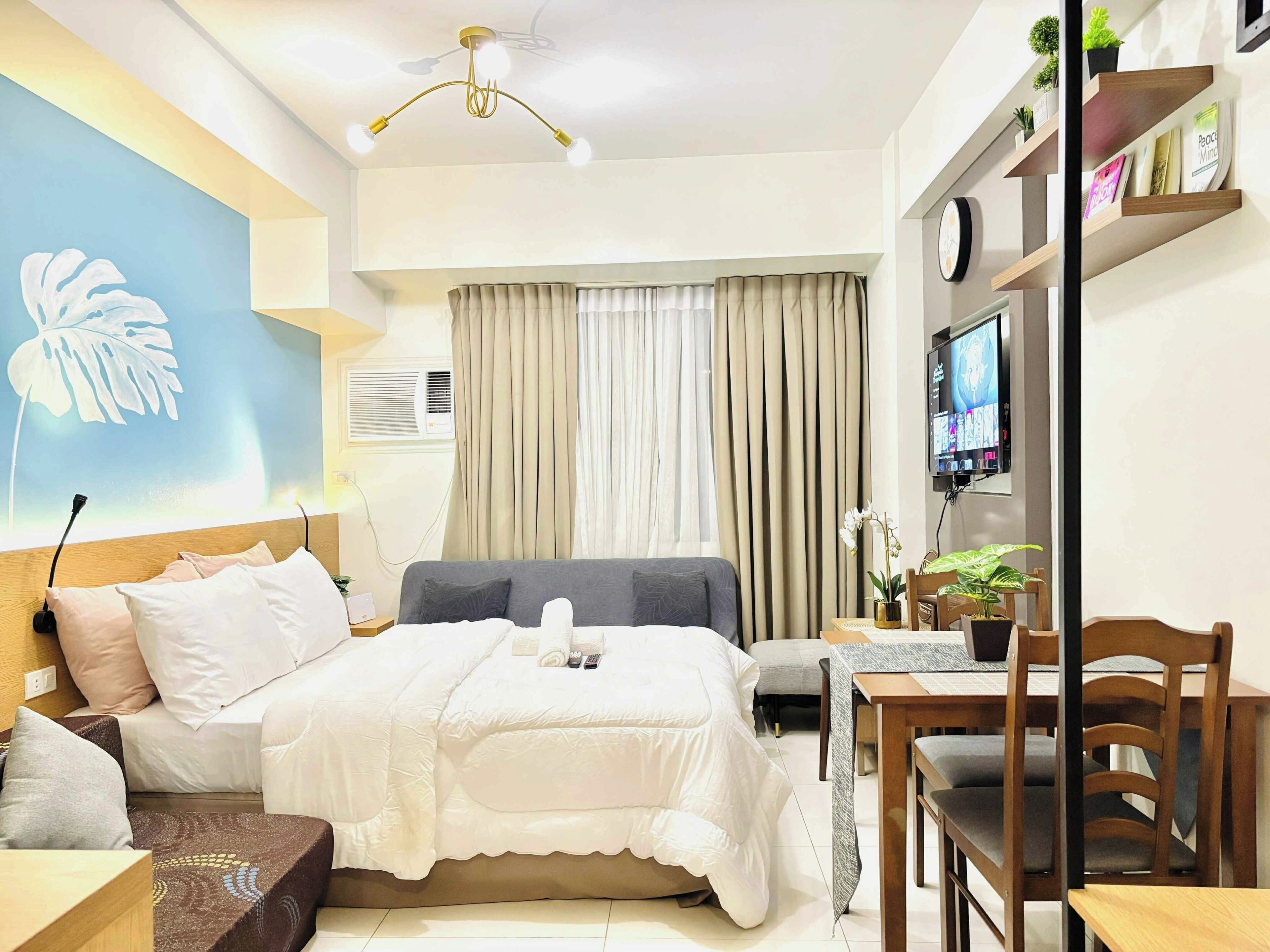 Une chambre d’hôtel équipée d’un lit, d’un bureau, d’une chaise, d’une télévision et d’une grande fenêtre avec des rideaux.