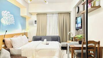 Une chambre d’hôtel équipée d’un lit, d’un bureau, d’une chaise, d’une télévision et d’une grande fenêtre avec des rideaux.
