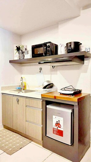 Cocina compacta con microondas, tostadora y refrigerador pequeño.