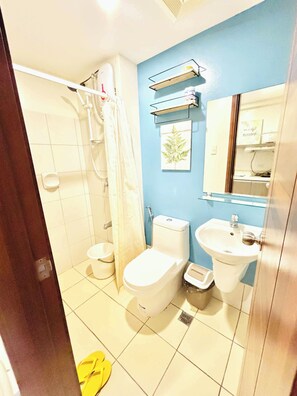A bathroom with a toilet, bidet, sink, and shower. There is a towel rack and a mirror above the sink. - MR BED-Skyline View Condo With POOL (Cebu City)