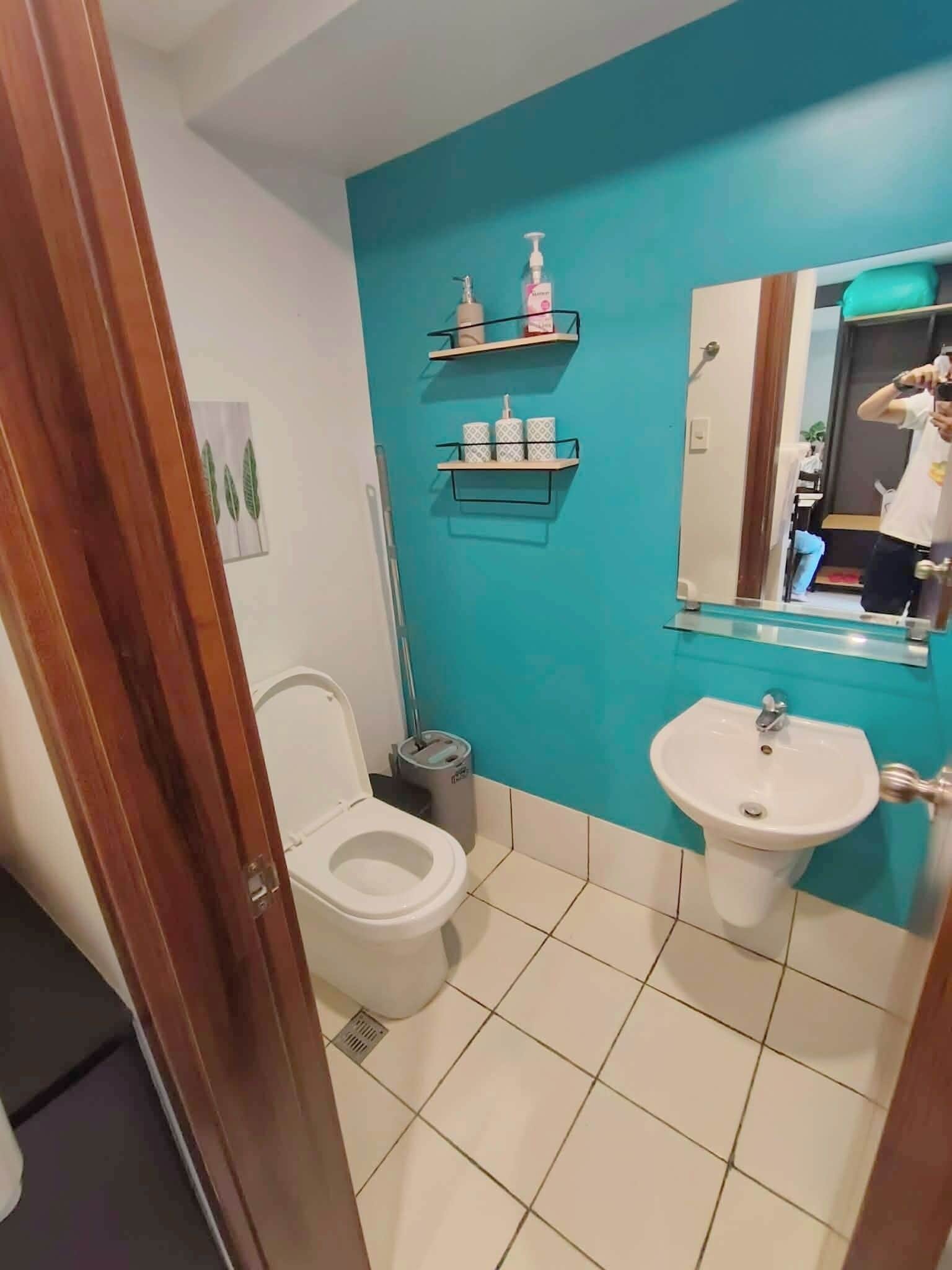 A bathroom with a toilet, sink, and two shelves with toiletries.