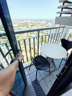 A balcony with a table and chairs, overlooking a cityscape.