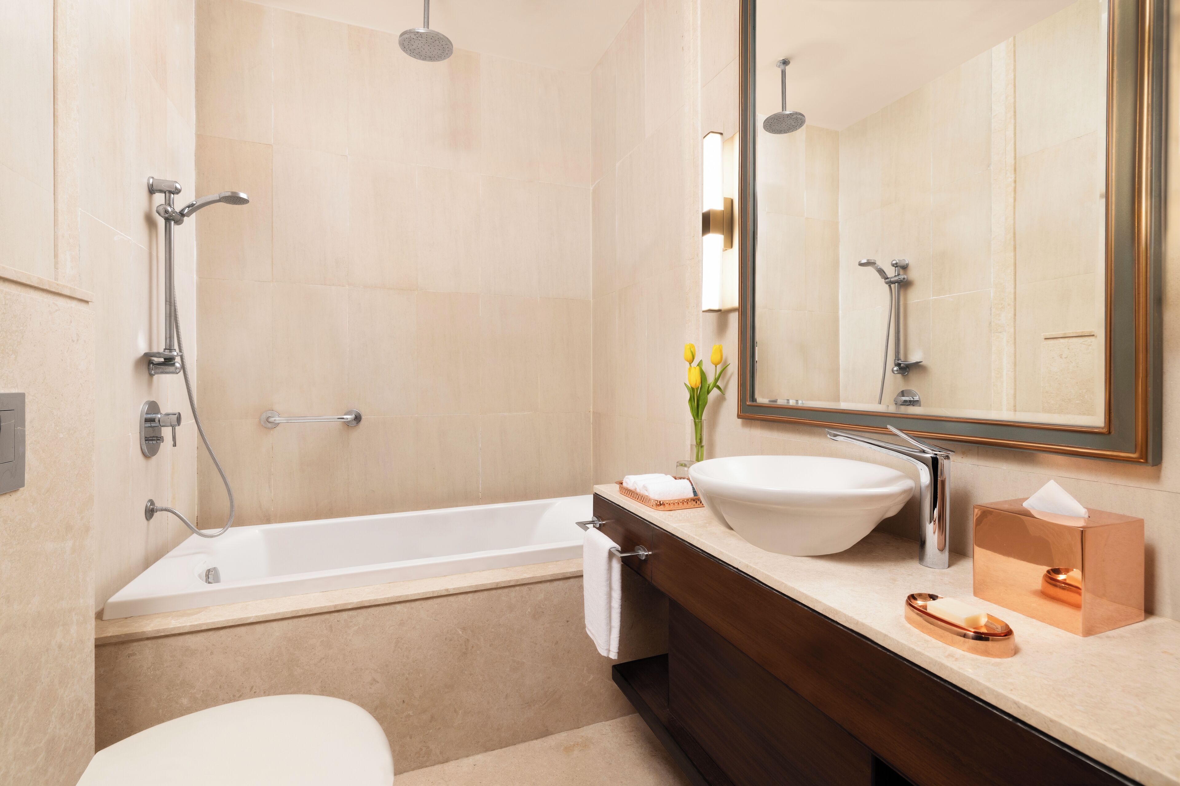 A modern bathroom with a bathtub, a sink, a mirror, and a toilet.