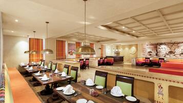 A spacious dining area with long tables, chairs, and hanging pendant lights.