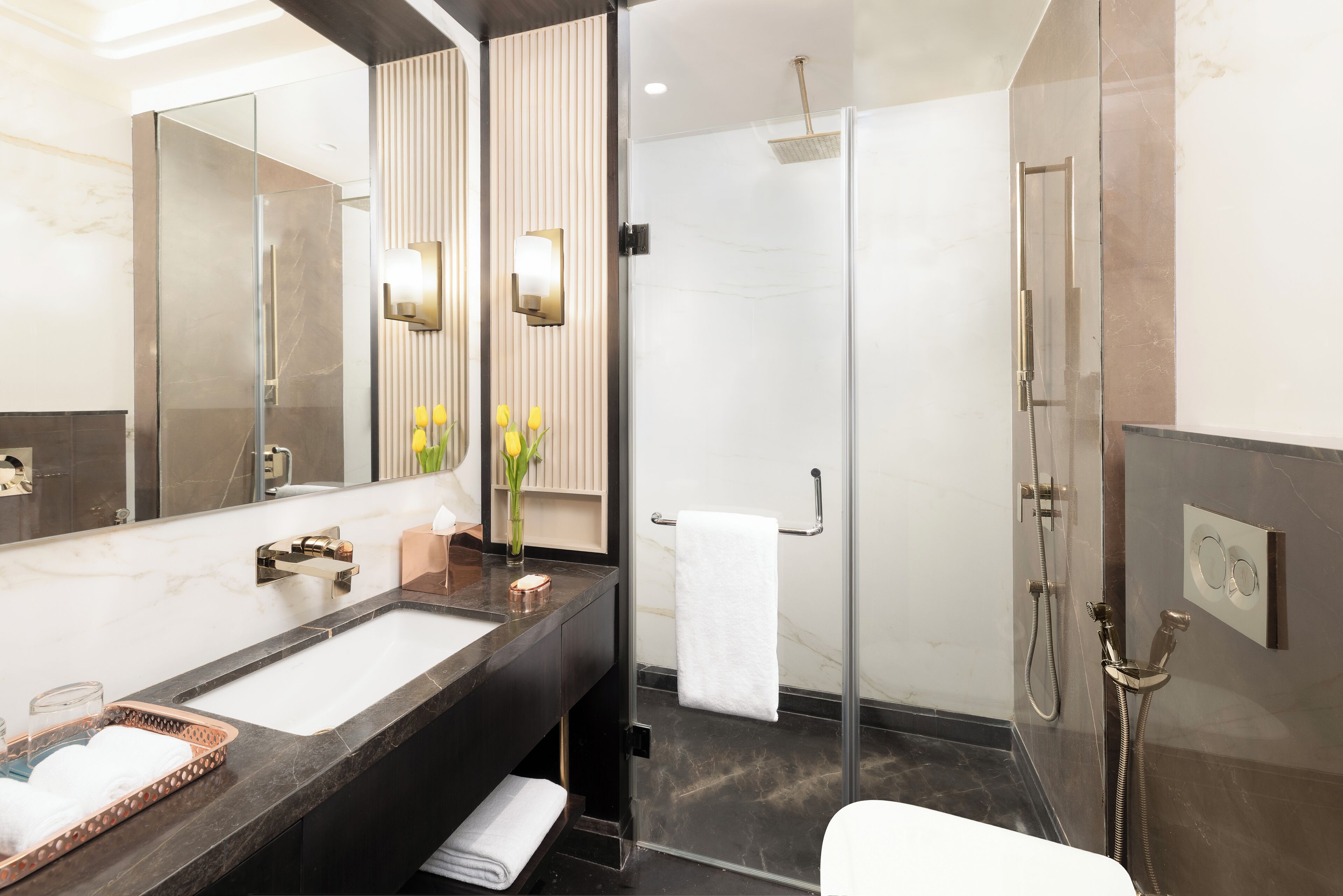 Un baño moderno con un espejo grande, lavamanos dobles, cabina de ducha de vidrio y un perchero para toallas.