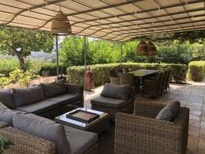 An outdoor patio with wicker furniture, a table, and hanging lanterns. - Provençal charm and serenity in the Saint-Tropez countryside (COGOLIN)