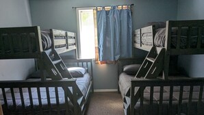 Una habitación con literas, una ventana con cortinas y suelo cubierto de alfombra.