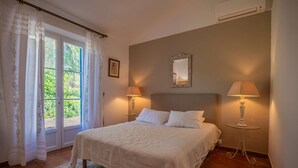 Une chambre à coucher avec un lit, deux lampes de chevet, un miroir et une fenêtre avec des rideaux.