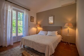 Ein Schlafzimmer mit einem Bett, zwei Nachttischlampen, einem Spiegel und einem Fenster mit Vorhängen.