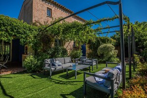 Eine Terrasse mit Gartenmöbeln, einer Pergola und einem Gebäude mit Ziegeldach im Hintergrund.