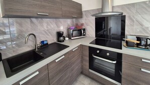 Una cucina moderna con lavello nero, elettrodomestici in acciaio inossidabile e mobili in legno.