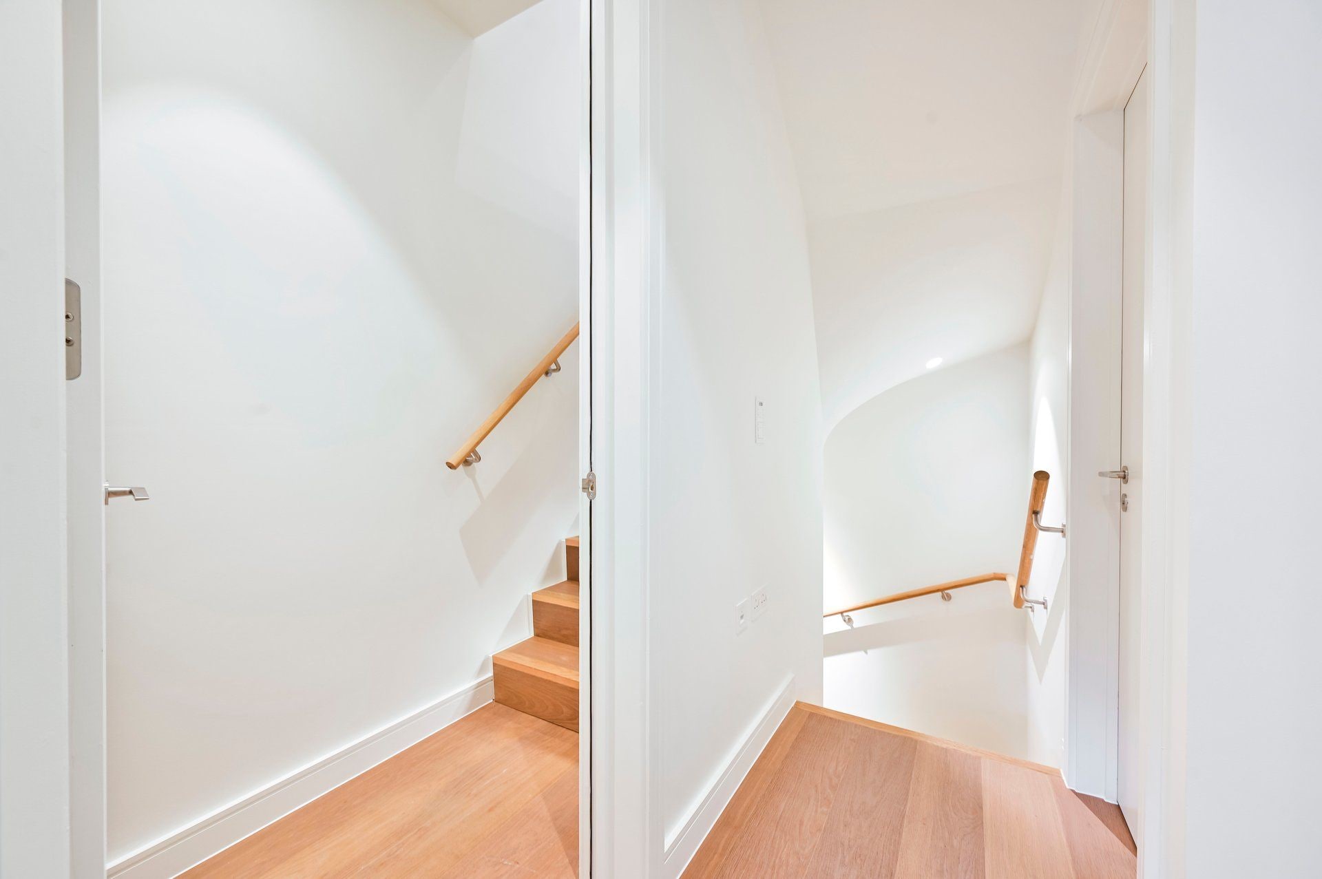 Una escalera con barandillas de madera y paredes blancas.