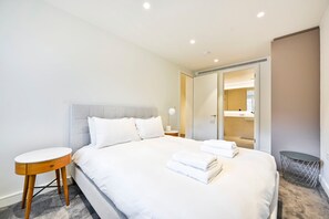 A hotel room with a bed, bedside table, and a bathroom visible through an open door. - Guestready - Stylish Living in Paddington (London)