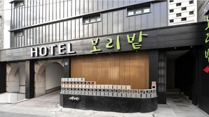 A hotel entrance with a modern facade, a wooden panel design, and a black and white color scheme. - Hotel Boribat SeokNam (Incheon)