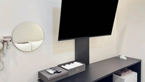 A modern hotel room with a flat-screen TV mounted on the wall, a bedside telephone, a small bedside table with a remote control and a tissue box, and a power outlet on the wall. - Hotel Boribat SeokNam (Incheon)