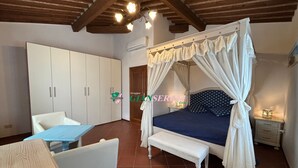 Un dormitorio con cama a dosel, un banco blanco, una mesita de noche y un armario.