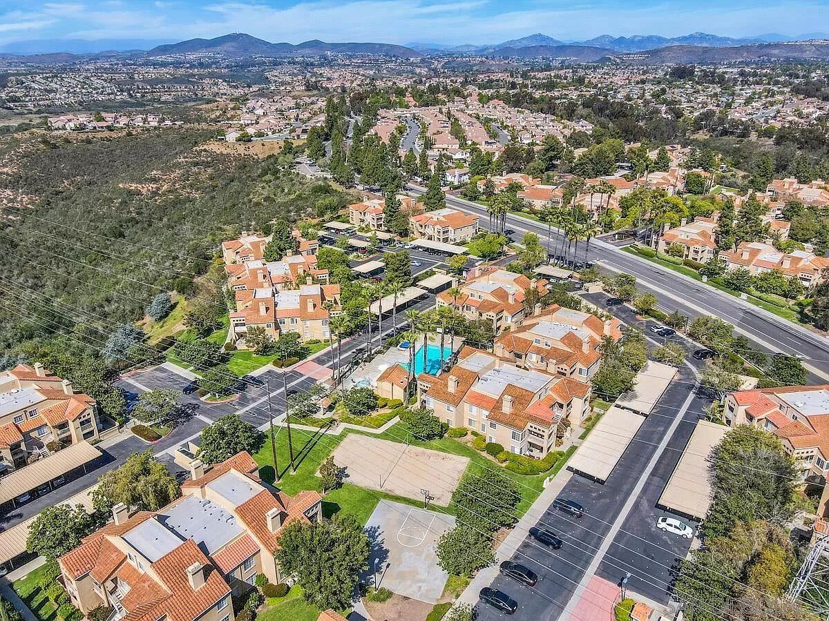 Vista aérea de um bairro residencial com casas, ruas e uma grande piscina azul.