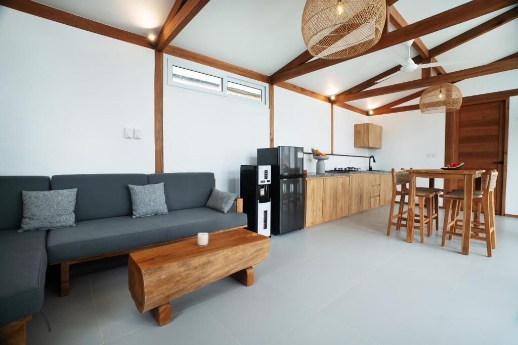 Una sala moderna con sofá, mesa de centro y comedor con sillas y mesa de madera.