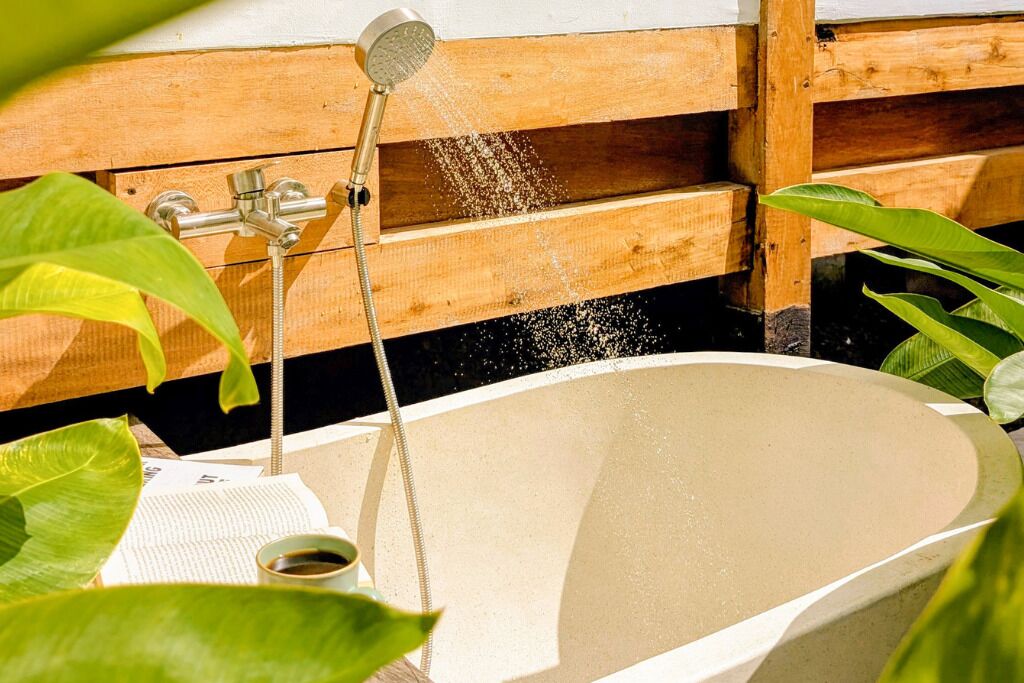 A bathtub with a showerhead, surrounded by wooden panels and green plants.