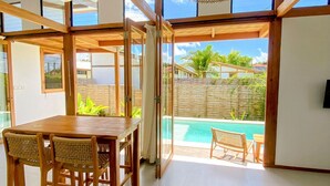 Une pièce moderne avec une table et des chaises en bois, une grande fenêtre et une vue sur une piscine.