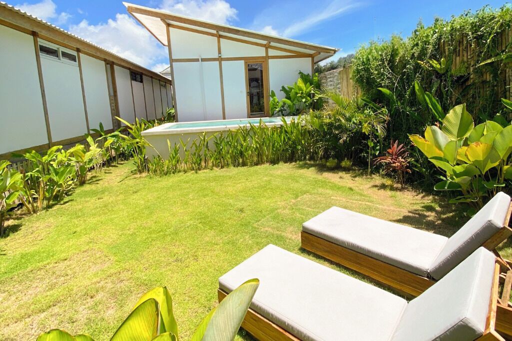 Una casa moderna con piscina, rodeada de exuberante vegetación y un césped cuidado.