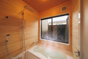 A wooden-paneled bathroom with a bathtub and shower. - GAON (Beppu)