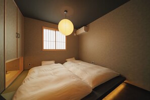 A bedroom with a large bed, a window, and a ceiling light. - GAON (Beppu)