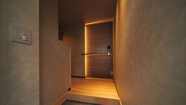 A narrow hallway with a wooden floor and a wall-mounted light fixture. - GAON (Beppu)