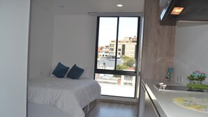 Una camera da letto con un letto, una finestra e un angolo cottura.