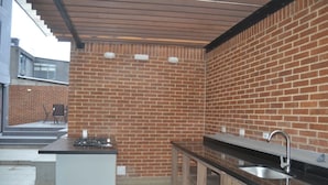 Una cucina moderna con parete in mattoni, piano cottura a gas, lavello e pensili in legno.