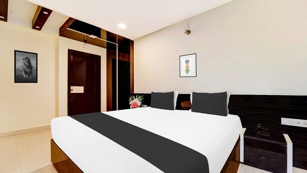 A modern bedroom with a large bed, a wooden headboard, a bedside table, and a nightstand. - Collection O Ramanathapuram (Ramanathapuram)