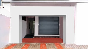 A modern building entrance with a closed roller shutter door and a red carpet leading to a brick-paved area. - Collection O Ramanathapuram (Ramanathapuram)