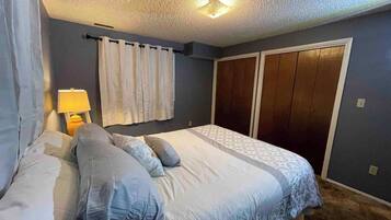 A bedroom with a bed, curtains, a nightstand, and a wardrobe.